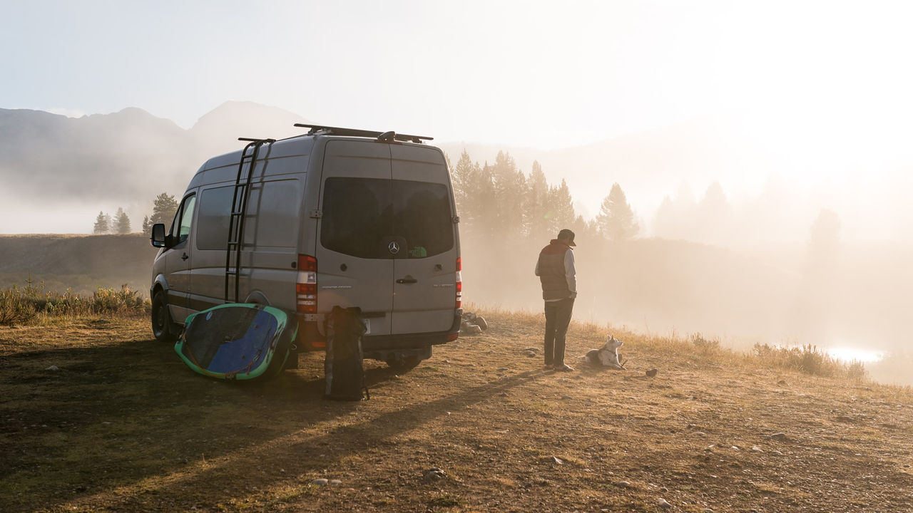 Camper van at mountain site with gear, depicting Webasto as system partner integrating roof systems and thermal management to enable off‑grid comfort and power.