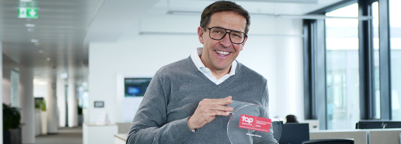 Mitarbeiter mit Top Employer Deutschland 2024-Auszeichnung in modernem Büro unterstreicht Webastos Reputation als Systempartner und Thema der Pressemitteilung.