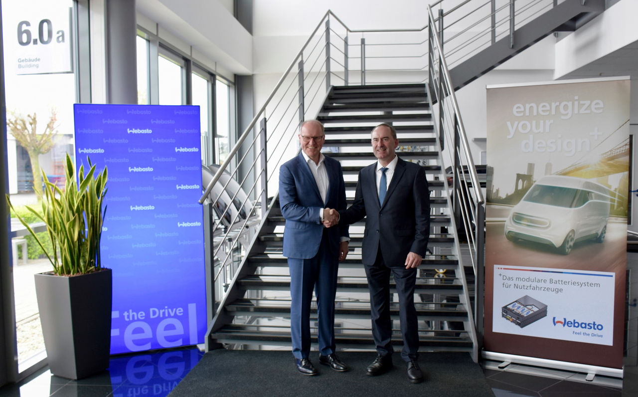 Handschlag beim Besuch des Webasto Kompetenzzentrums Schierling vor Bannern zu modularen Batterien; Pressebild zur Standort- und Partnerschaftskommunikation.