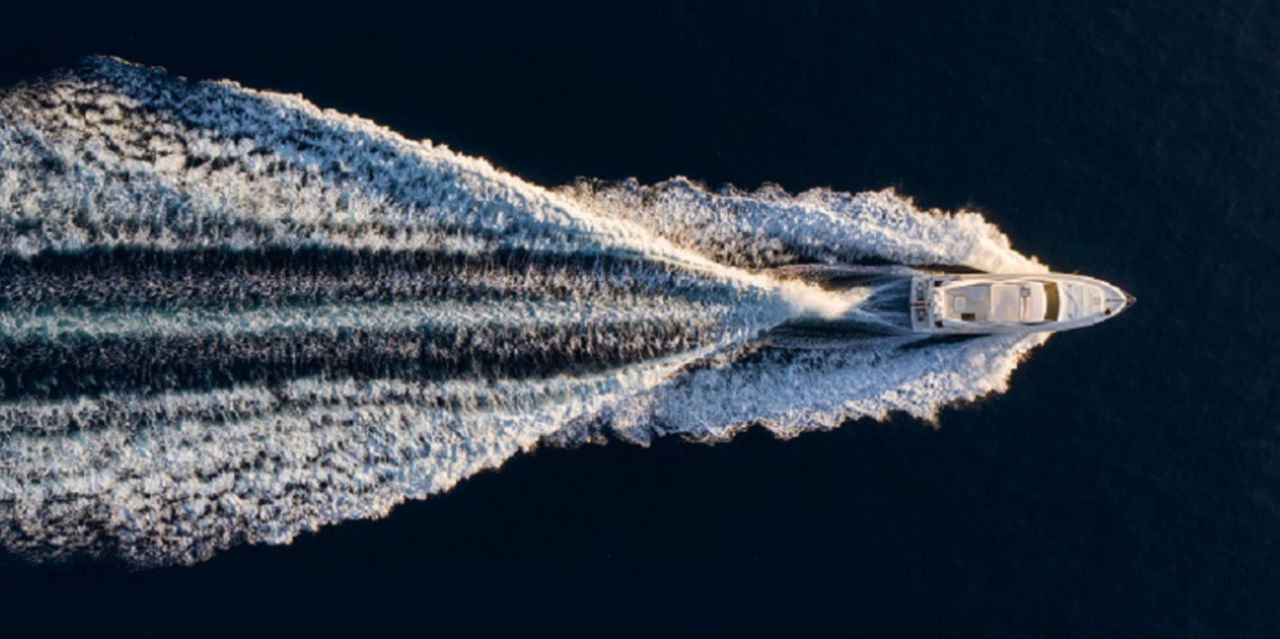 Luftaufnahme einer schnellen Yacht mit prägnantem Bugwasser, symbolisiert Webastos maritime Kompetenz und Produktpräsenz in Pressemitteilung zu Metstrade 2025.