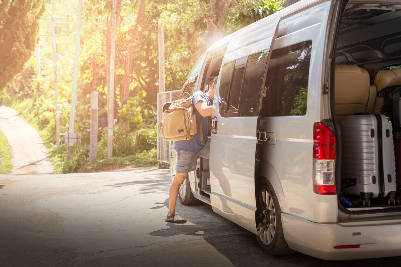 Passenger entering climate-controlled minivan with luggage, demonstrating Webasto integrated air-conditioning and thermal management for passenger transport.