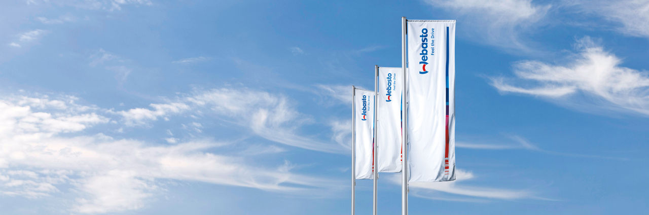 Corporate hero motif with three Webasto flags against a clear sky, reinforcing brand identity and system-partner positioning for The Group section.