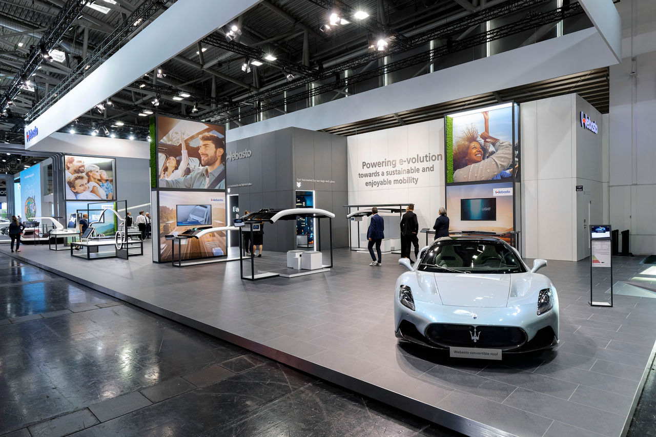 Webasto as system partner at an international trade show presenting convertible roof systems and e-mobility solutions, featuring a Maserati demonstrator car.
