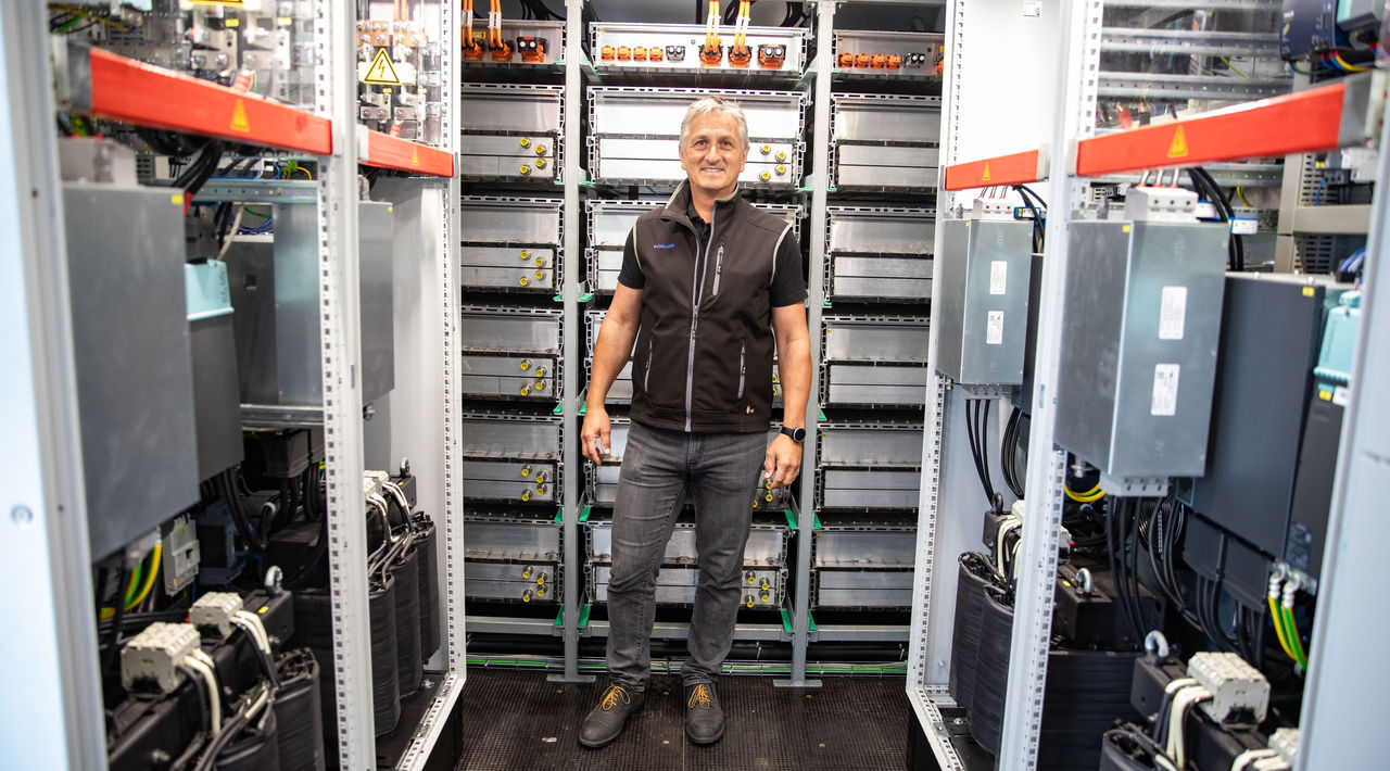 Plant manager supervising Webasto high-voltage battery assembly in a production cell, showcasing vehicle electrification and systems-partner expertise.