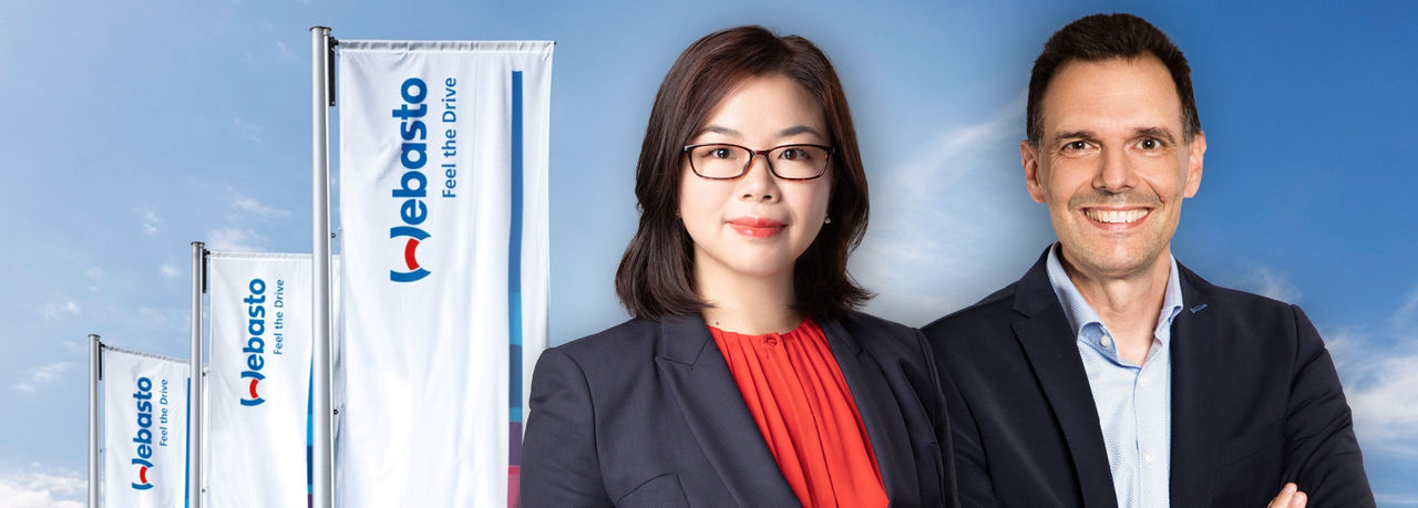 Corporate header for The Group leadership page: two Webasto executives with branded flags and sky, reinforcing Webasto’s positioning as a global systems partner.