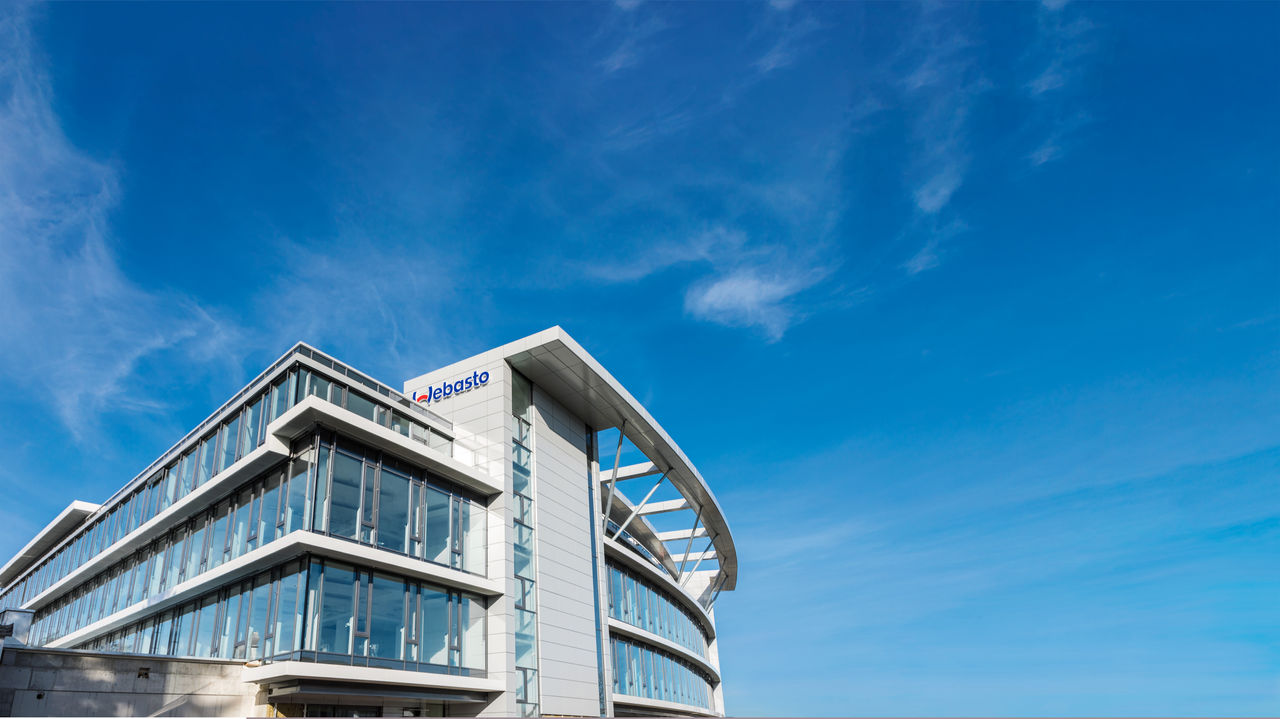 Webasto headquarters façade with logo under clear sky, hero header for The Group pages conveying global systems partner identity and corporate presence.