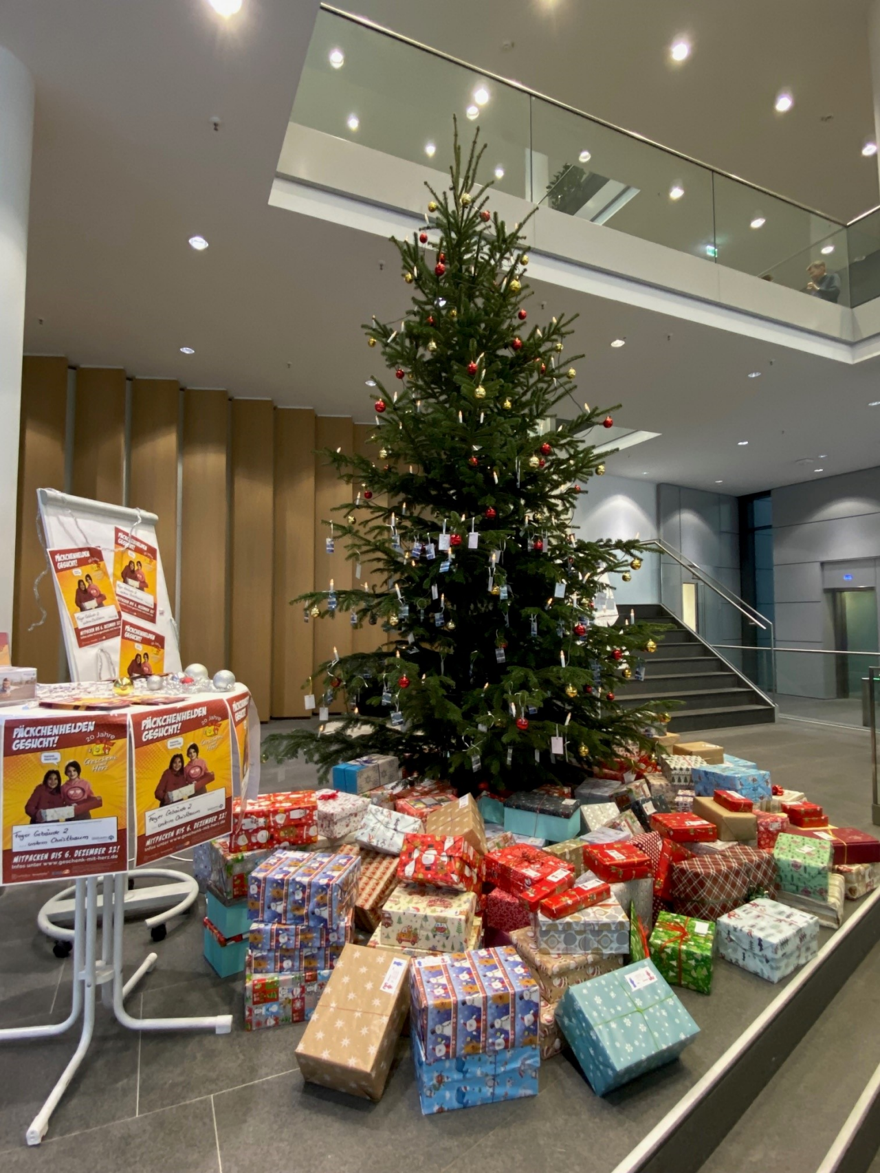 Webasto lobby Christmas tree and wrapped gifts for 'Päckchenhelden' holiday donation campaign, highlighting Webasto Foundation employee engagement and CSR
