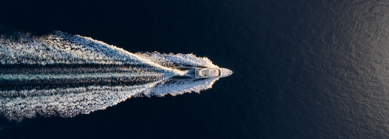 Aerial top view of a motor yacht carving a wake on open sea, for vehicle solutions - marine, illustrating Webasto's marine electrification and thermal systems.