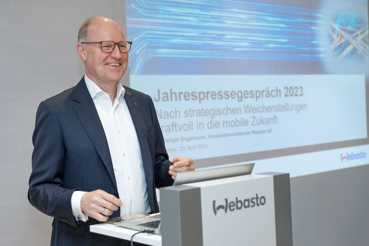 Webasto newsroom asset (DE): presenter at branded lectern during 2023 annual press conference, underlining corporate strategy and vehicle electrification.