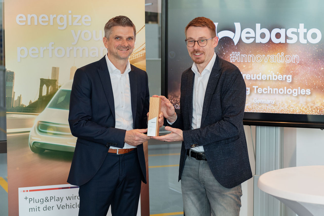 Webasto newsroom press: executives exchanging an innovation award symbolizing partnerships in vehicle electrification and roof system advancements.